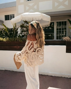 Detailed view of bohemian hollow crochet pattern on beige off-shoulder vacation top