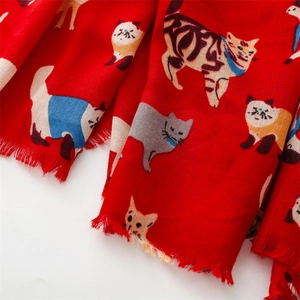 Detailed close-up of red cotton linen scarf with cartoon cat prints and soft tassel edges