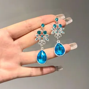 Dettaglio degli orecchini vintage con cristallo blu a goccia e decorazioni floreali