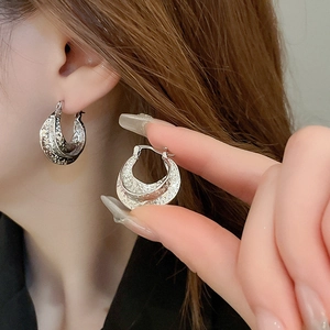 Detail of silver crescent hoop earrings with hammered texture and minimalist style