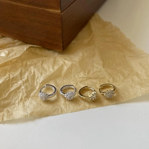 Close-up of gold and silver flower-shaped stud earrings with cubic zirconia on brown paper