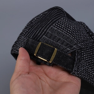 Detail of adjustable metal buckle and black fabric strap on the gray plaid ivy cap