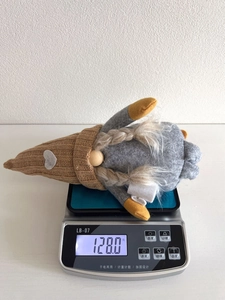 Macro view of Christmas gnome plush doll on a scale weighing 128 grams
