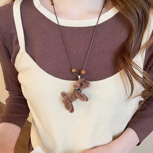Close-up of a plush puppy pendant necklace with wood beads on a model's neck