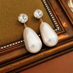 Détail macro de boucles d'oreilles vintage dorées avec cristaux et perles blanches en goutte