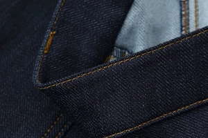 Gros plan des coutures jaunes contrastées sur le tissu en denim bleu foncé de qualité