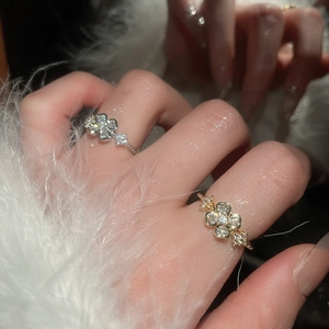Detailed view of gold and silver clover flower rings with zircon crystals on model hand