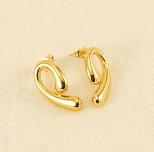 Detailed top-down view of 18K gold plated teardrop earrings on beige linen fabric
