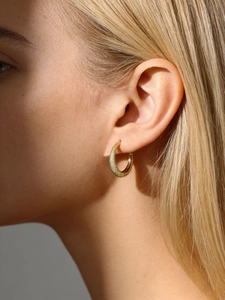 Close-up of golden frosted S925 sterling silver hoop earring worn on woman's ear