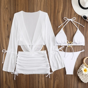 Flat lay of white 4-piece bikini set with mesh cover-up and gold heart ring detail