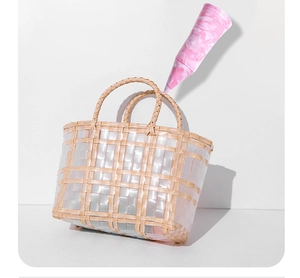 Detail of woven beige straw handbag with transparent strips and dual round handles