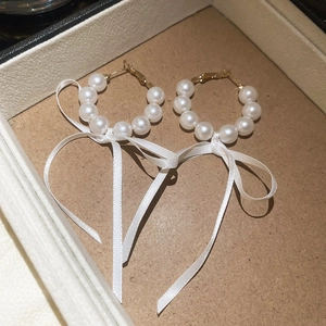 Detailed view of elegant white pearl hoop earrings with delicate satin ribbon bows