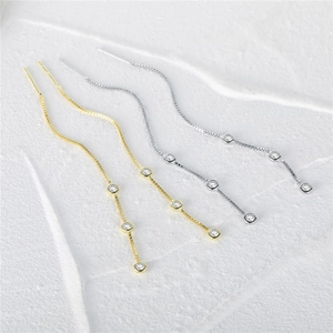 Detail of silver and gold tassel earrings with four sparkling round zircons on chains