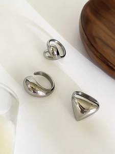 Detailed view of silver stainless steel geometric rings set on a white podium display