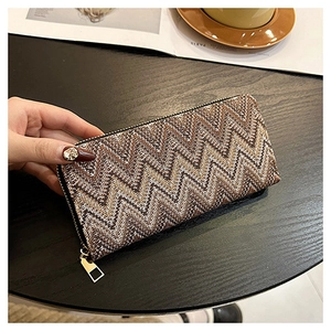 Macro detail of long zip-around wallet featuring brown zigzag knit pattern and gold zipper