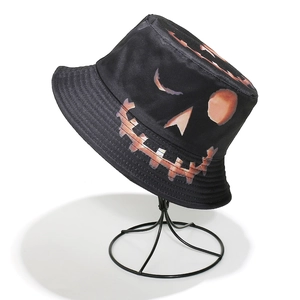 Detailed view of black Halloween bucket hat with orange pumpkin face print on a stand