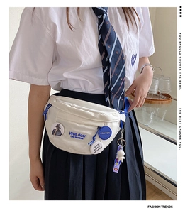 Close-up of white canvas chest bag with Well doer lettering and astronaut charm