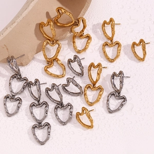 Macro detail of heart-shaped earrings with irregular hammered texture on a water droplet surface