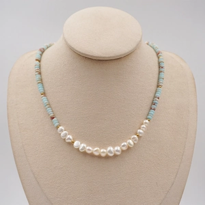 Colorful freshwater pearl necklace with light blue beads and gold accents on a bust