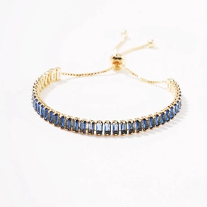 Detail view of gold adjustable sliding bracelet with blue zircon stones and size specs