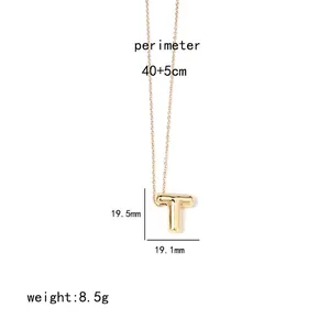 Detailed view of golden letter T pendant necklace with rounded texture on white background