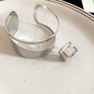 Detail of silver irregular hollow open bangle and minimalist wide ring on white tray