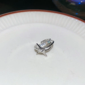 Macro shot of silver star-shaped ear cuff with sparkling cubic zirconia on ceramic plate