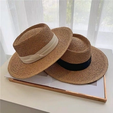 Detail of flat top straw boater hats with black and beige ribbons on a magazine