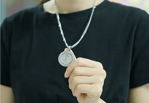 Detailed view of silver portrait pendant with zircon border on snake bone chain