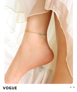 Detail of a gold titanium anklet with blue beads and wing charm on female ankle