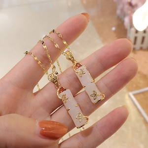 Close-up of bamboo-shaped white jade pendant with gold leaves and inlaid rhinestones