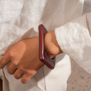 Close-up of deep reddish-brown geometric acrylic bracelet with matte finish on wrist