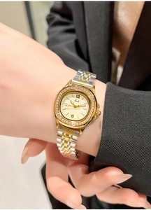 Close-up of luxury gold-tone watch with sparkling diamond bezel on a woman's wrist