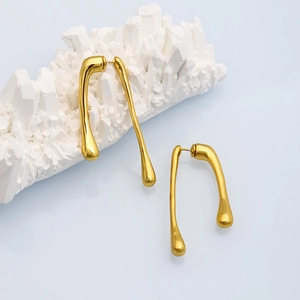 Detail of gold liquid metal teardrop earrings displayed on white crystal stones