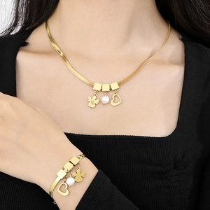 Detail of gold snake chain necklace and bracelet set with heart and pearl charms