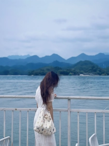 Floral print cotton canvas tote bag carried by a model against a scenic lake backdrop