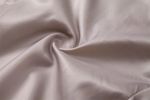 Macro d'un tissu champagne au lustre soyeux et drapé doux pour costumes de luxe