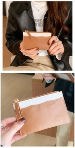 Close-up of brown and white leather coin purse with zipper and wristlet strap