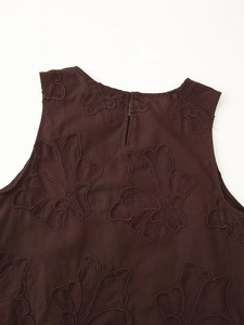 Détail de l'encolure ronde et fente au dos avec broderie florale sur tissu marron foncé