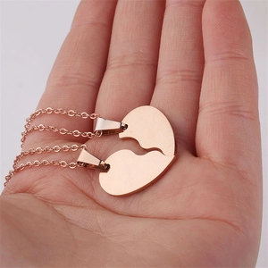 Rose gold stainless steel broken heart necklace for couples held by hand
