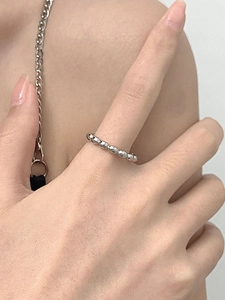 Detailed view of silver beaded ring with faceted surface on female model's finger