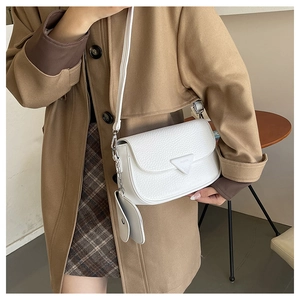 Gros plan d'un sac à bandoulière blanc texturé avec un petit porte-monnaie assorti