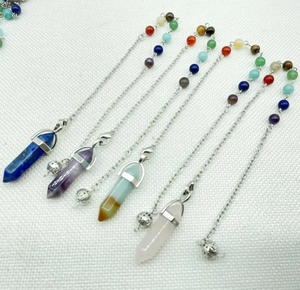 Gedetailleerd overzicht van zeshoekige kristallen pendels met chakra-kralen en zilveren ketting