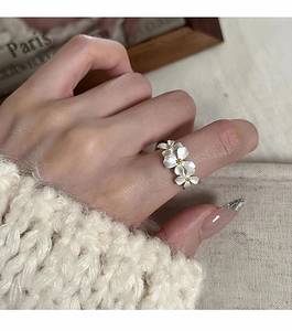 Close-up of a sweet Korean flower ring with three white petals on a model's finger