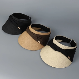 Detail of woven straw texture and small gold metal tags on three open-top sun visors