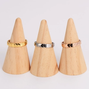 Three mermaid scale rings in gold, silver, and rose gold on wooden cone displays
