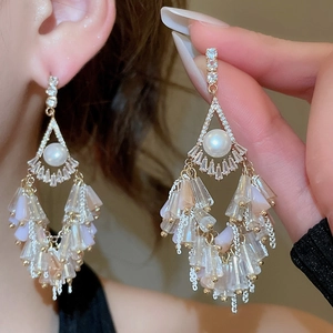 Detail of fan-shaped tassel earrings with pearls and gradient crystal beads on a model
