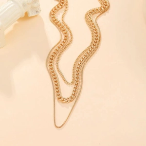 Detail of triple-layer gold necklace featuring chunky cuban links and dainty ball chains