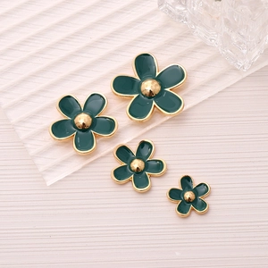 Detail of four green enamel five-petal flower charms with gold edges in various sizes