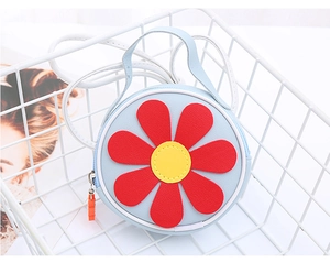 Dettaglio di una borsa a tracolla rotonda blu con girasole in pelle PU testurizzata